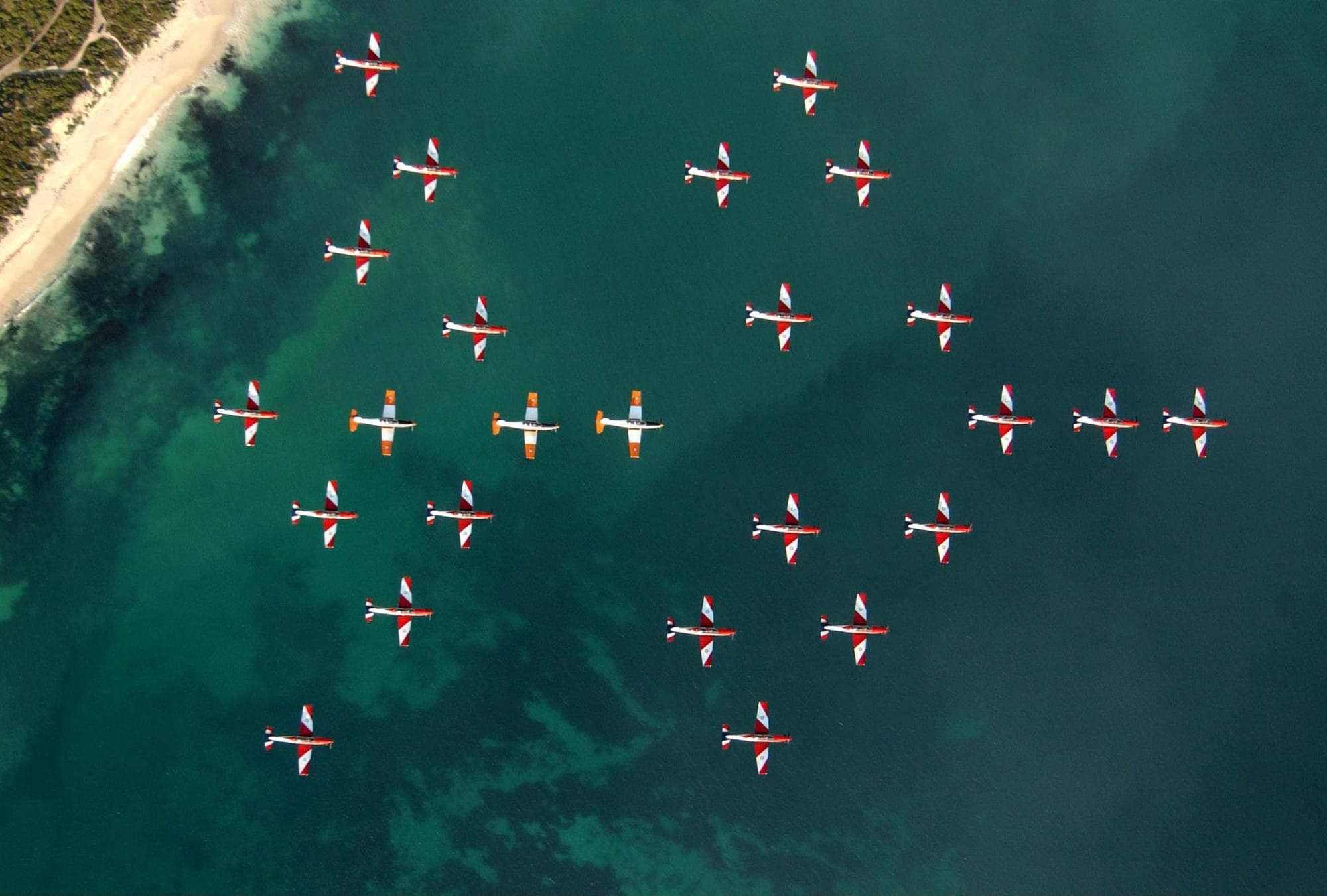 Twenty-four aircraft holding a single formation, seen from above